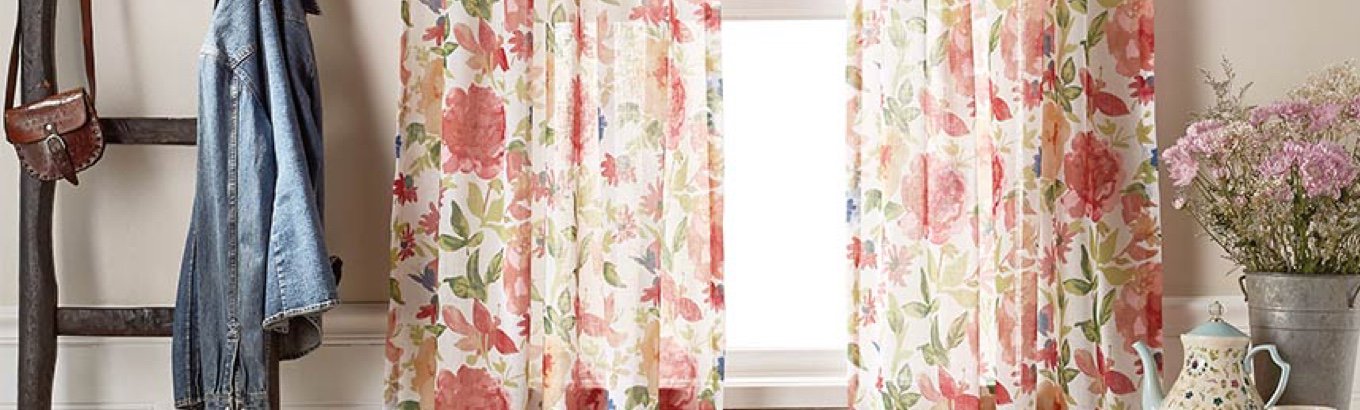 A set of floral curtains in a window. Starts the window treatment ideas blog post on dxfairmall.com.